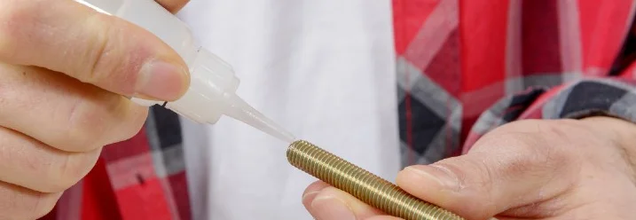 Person trägt Kleber auf Schraube auf